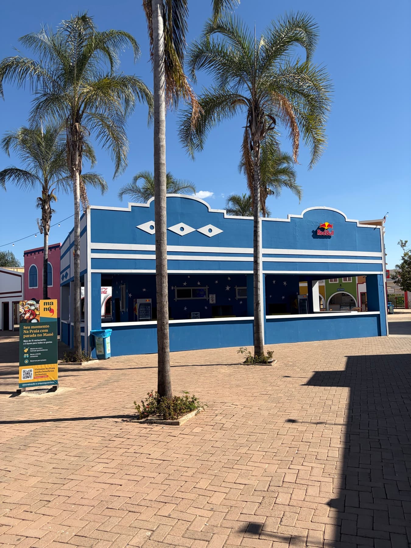 Fachada azul do Na Praia entre palmeiras